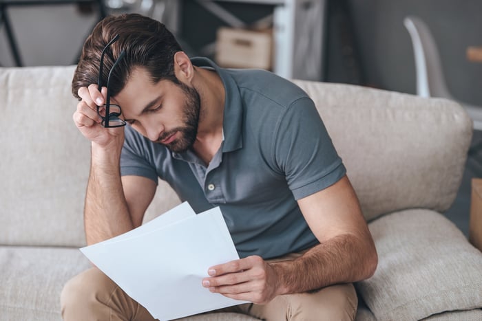 Man sitting on couch, bent over looking at documents