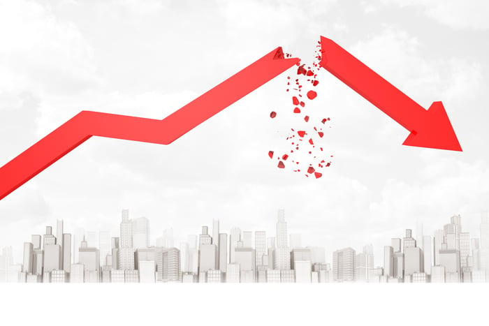 Red stock arrow breaking up and showering down in pieces over a city below