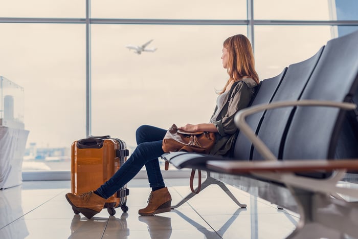 Woman seated in airport watching plane through window