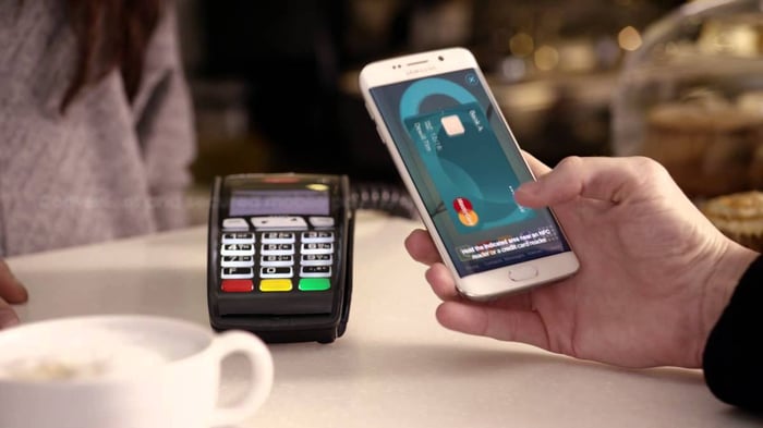 Mastercard on phone being used to pay for goods at a cafe.