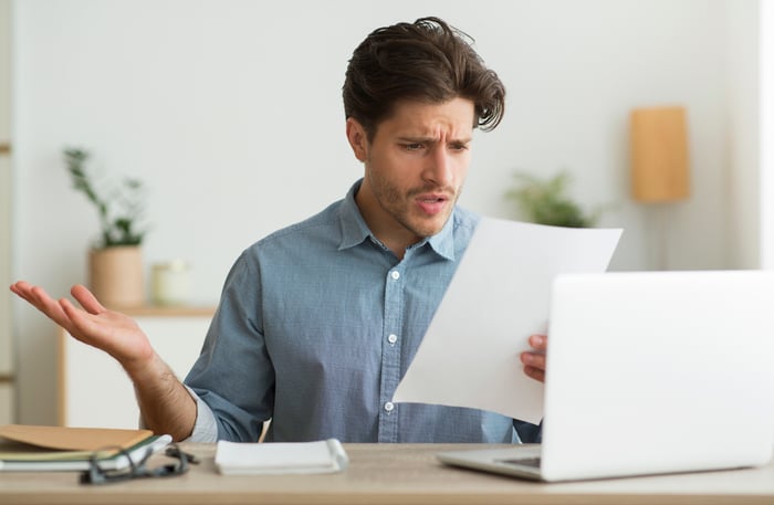 Man with shocked expression at laptop reading document