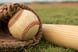 a baseball in a glove and a baseball bat lying on grass