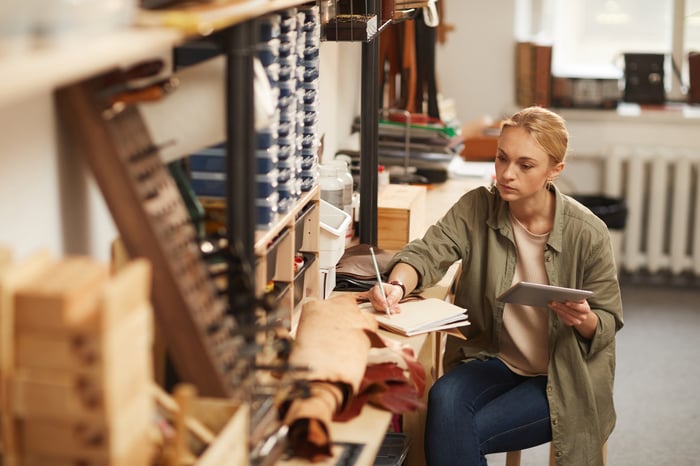 Woman in workshop writing in notebook