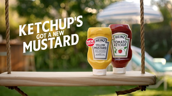 A Heinz ketchup and mustard bottle next to each other on a swing
