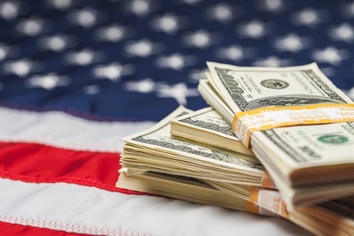 Four bundled stacks of cash lying atop an American flag.