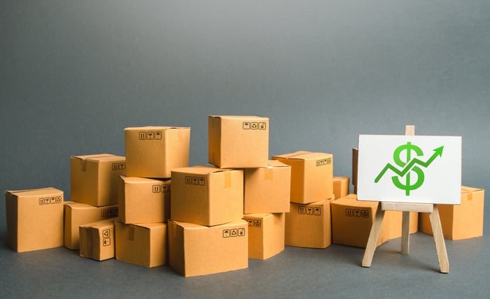 boxes sit on a floor next to an easel with a dollar sign image on it.