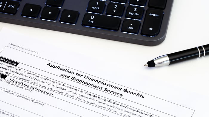 Application for unemployment benefits next to pen and computer keyboard