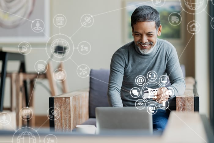 Smiling man using a credit card to make an e-commerce purchase on a laptop.