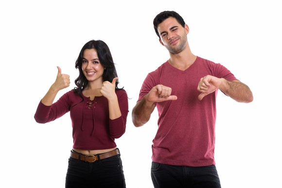Woman giving two thumbs-up next to man giving two thumbs-down