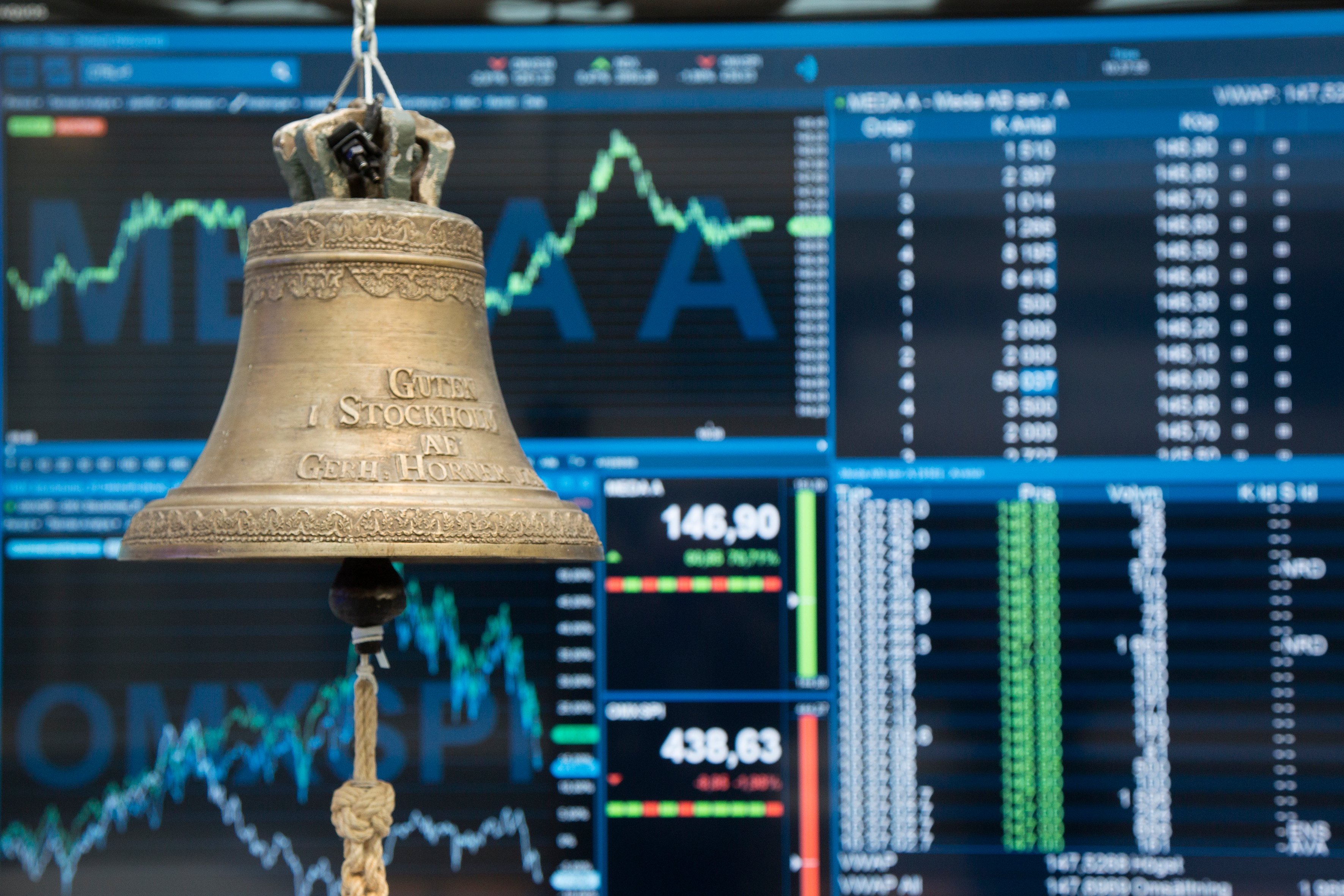 Bell at the Nasdaq with display screens in the background