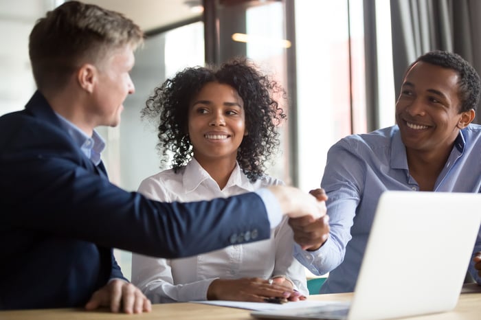 A bank manager shaking hands with prospective clients in his office.