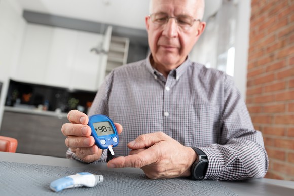 A senior man checking his blood sugar levels with a glucometer.