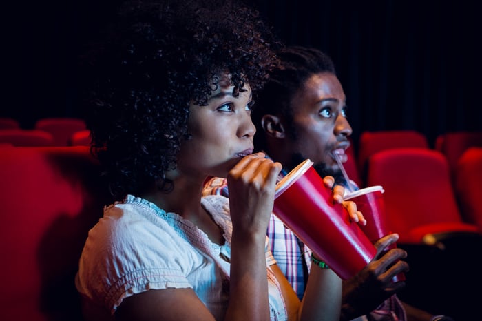 Two people drinking sodas in a movie theater