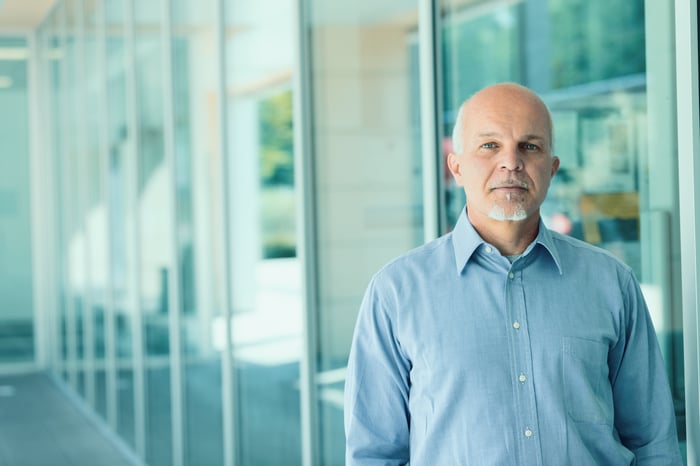 Older man with serious expression standing outside a building