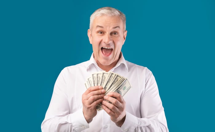 Smiling man holding a bunch of hundred-dollar bills