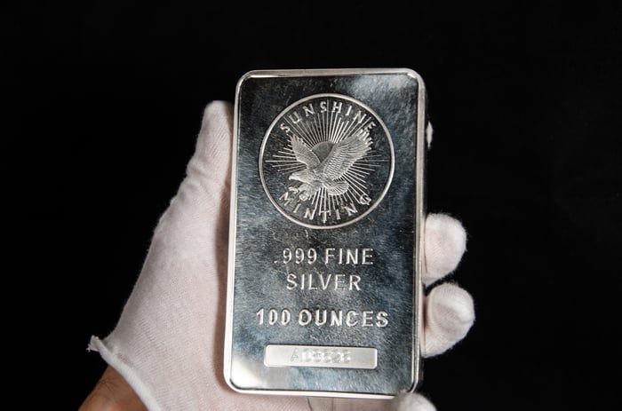 A gloved hand holding a silver bar