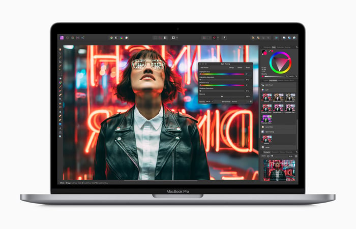 A woman at night wearing a leather jacket and glasses looking upward, shown on an Apple Macbook Pro.