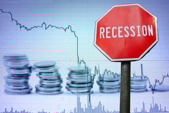 Red "recession" sign in front of a chart with a declining line.