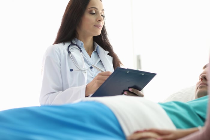 A female doctor standing over a male patient in a bed