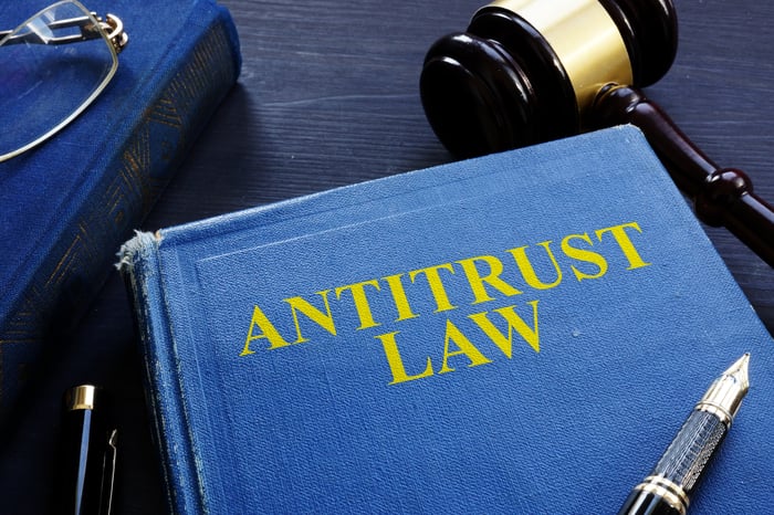 A book titled Antitrust Law with a gavel next to it and a fountain pen on top of it.