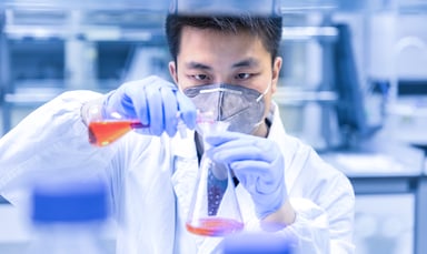 A scientist pouring a liquid into a container in a laboratory