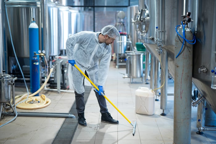 A worker cleans a manufacturing facility with industrial supplies.