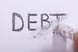 A pencil erasing the word debt.