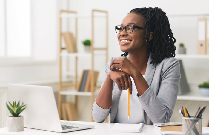 A smiling woman at a desk with shelving in the background