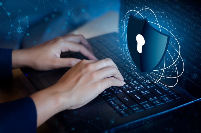 Hands positioned on a laptop keyboard with a floating shield icon hovering above