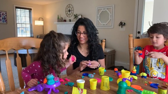 An adult and two children playing with Hasbro's Play-Doh.