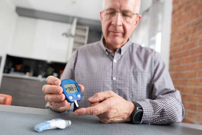 A senior man using a glucometer to measure his blood sugar level.