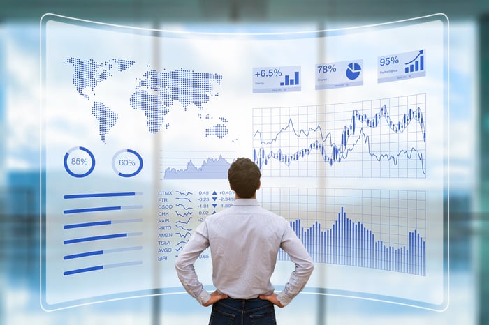 A man looking at a wall screen that includes a map and various charts