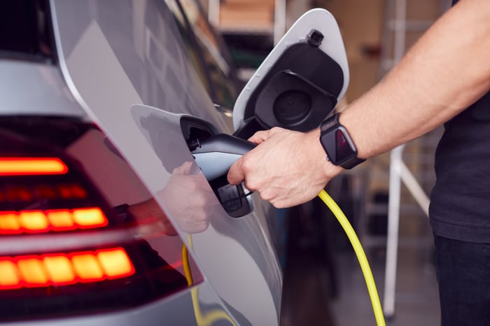 A Man attaches a power cable to an electric vehicle.