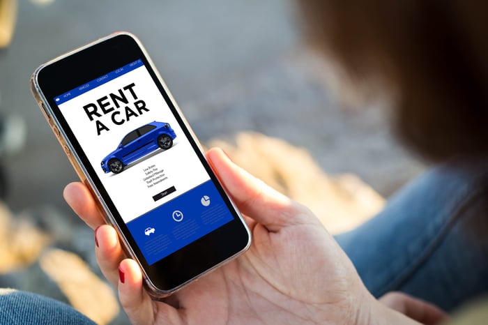 A woman looking at a car rental app on a smartphone.