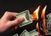 Hand holding burning hundred dollar bills