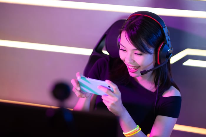 Gamer wearing a headset livestreaming on a smartphone. 