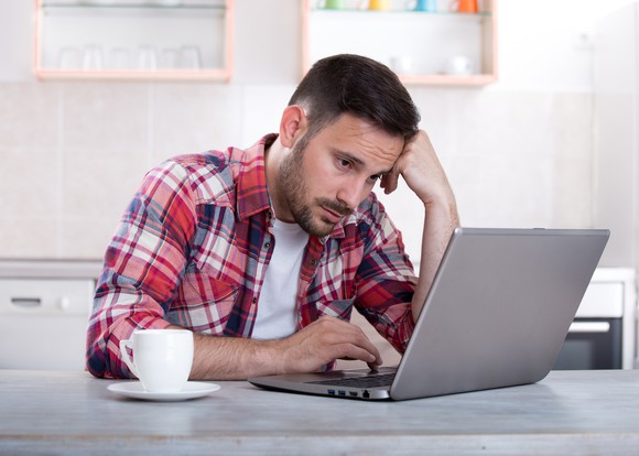 Man with sad expression looks at a laptop
