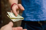 Person Handing Over a $5 Bill -- GettyImages-1264840206