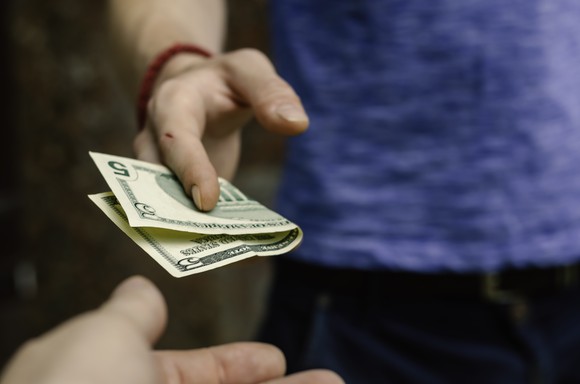 Person handing over a $5 bill