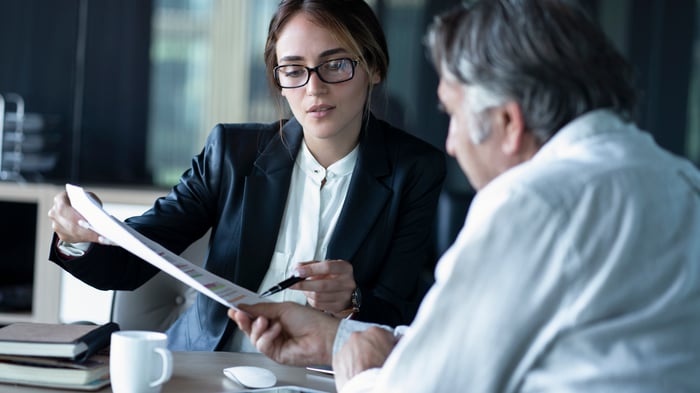 Two business professionals discuss a contract.