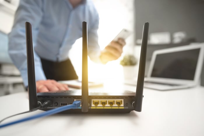 a wireless router in the foreground a man using a smart phone in the background