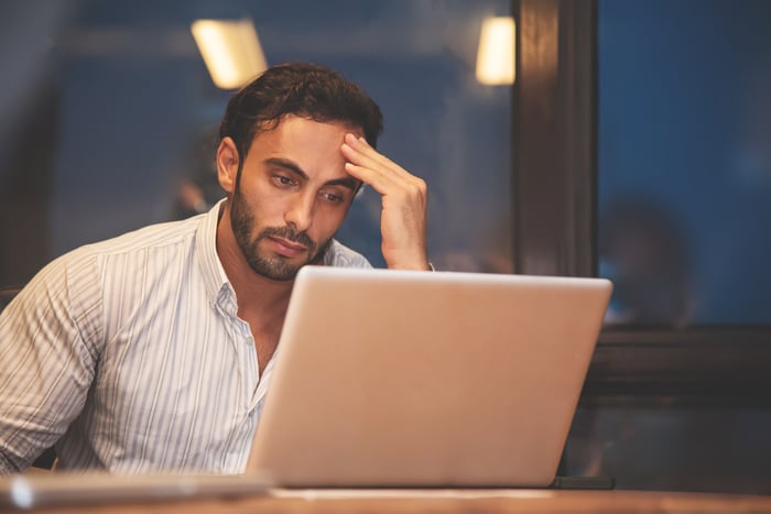 Person staring at laptop with serious expression. 