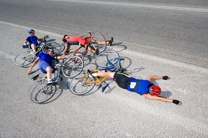 Four bicyclists who have crashed, lying in the road. 