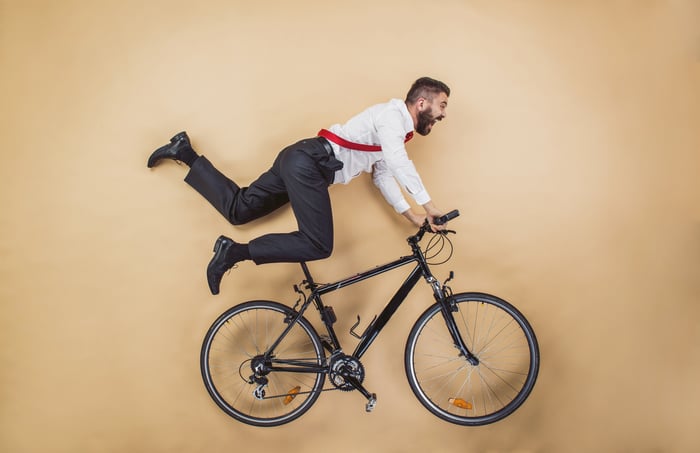 Man in office clothes in action over a bike, possibly about to fall.