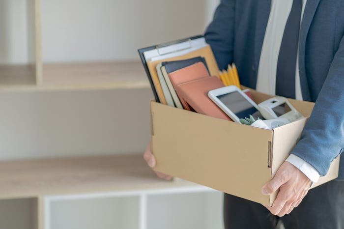 Businessman exiting his former place of employment, carrying a box of personal belongings.