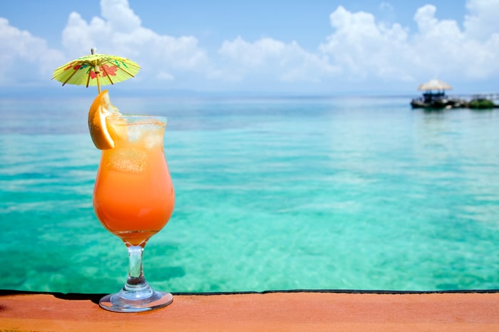 A tropical drink with an umbrella and a view of the ocean.