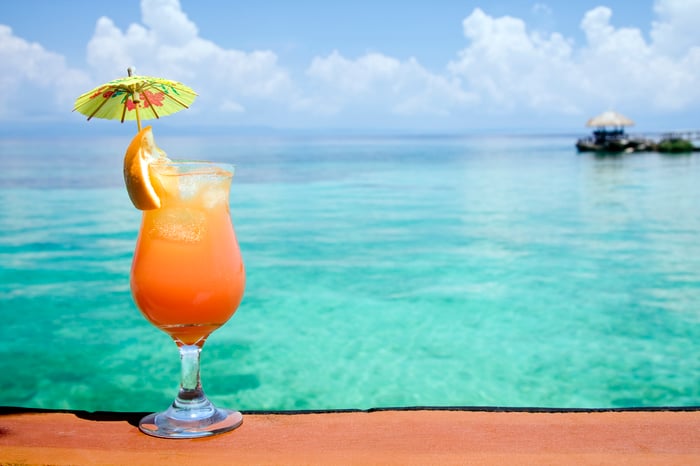 A tropical drink with an umbrella and a view of the ocean. 