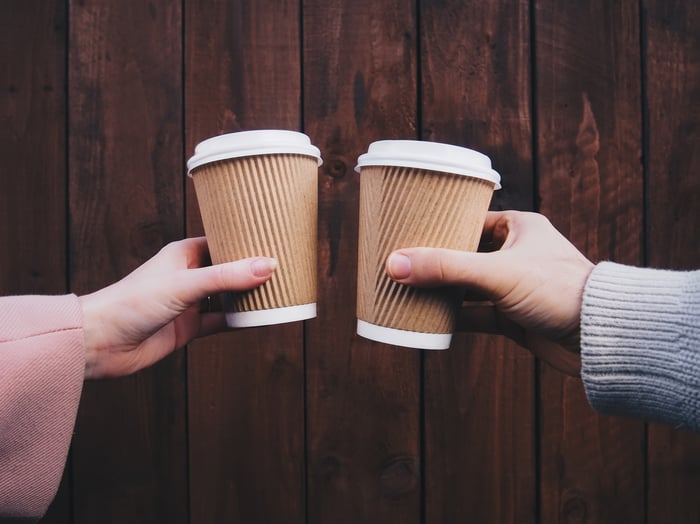 Two cups of coffee are juxtaposed against a wood panel background.