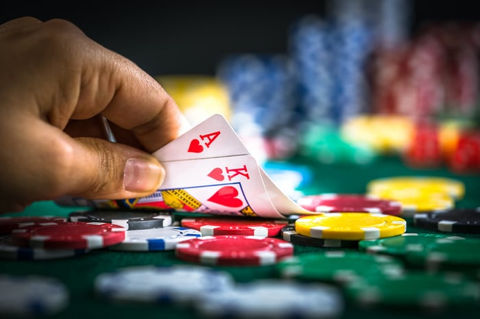 A hand lifting up cards on a poker table filled with chips