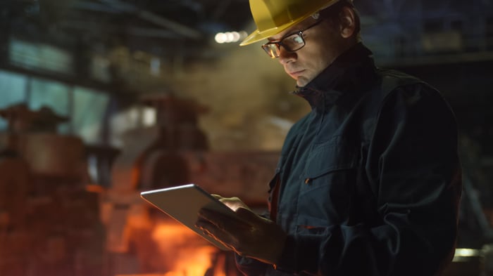 Man writing on notebook while standing in a steel mill